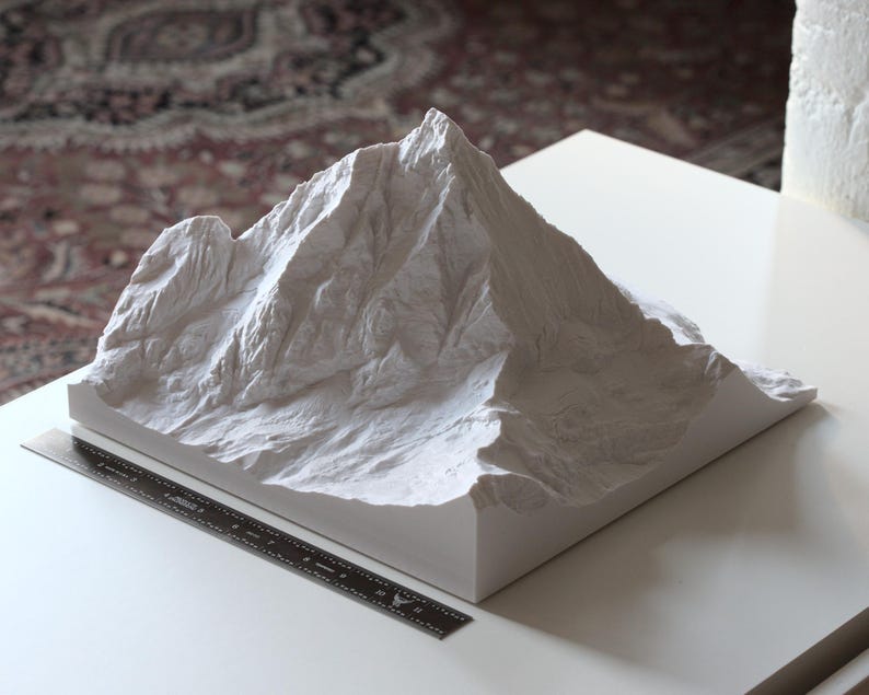 Puede incluir: Un modelo de monta&ntilde;a de yeso blanco. El modelo est&aacute; detallado con picos y valles realistas.
