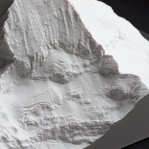 Puede incluir: Primer plano de un modelo de cordillera de monta&ntilde;as impreso en 3D blanco texturizado. El modelo est&aacute; hecho de un pl&aacute;stico blanco liso y tiene una textura realista y detallada.