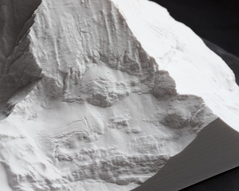 Puede incluir: Primer plano de un modelo de cordillera de monta&ntilde;as impreso en 3D blanco texturizado. El modelo est&aacute; hecho de un pl&aacute;stico blanco liso y tiene una textura realista y detallada.