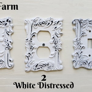 May include: White distressed decorative light switch covers with floral and scrollwork designs. The image shows three different styles: a single switch, a double outlet, and a double switch. The text "CozyRoseFarm" and "White Distressed" are visible.