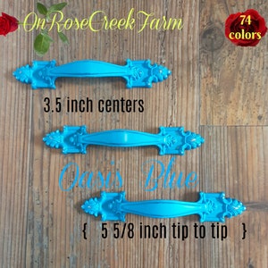 May include: Three turquoise cabinet pulls with ornate detailing. The top pull has 3.5 inch centers, and the bottom pull is 5 5/8 inches tip to tip. The text "Oasis Blue" is written on the image, along with the text "On Rose Creek Farm" and "74 colors".