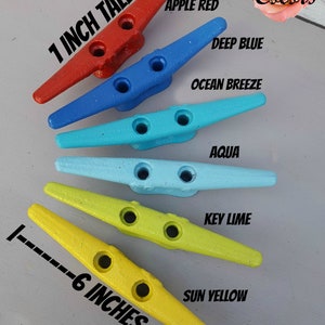 May include: Six colorful boat cleats in shades of red, blue, aqua, and yellow, each 6 inches long and 1 inch tall. Colors include Apple Red, Deep Blue, Ocean Breeze, Aqua, Key Lime, and Sun Yellow. The image also includes the text "74 Colors".
