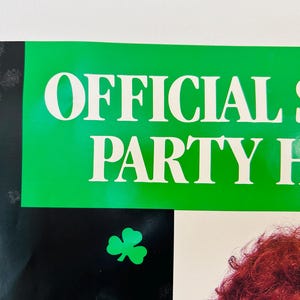 May include: A poster with the words "OFFICIAL ST. PARTY HEADQUARTERS" in white letters on a green background. A green shamrock is in the lower left corner. The background is black.
