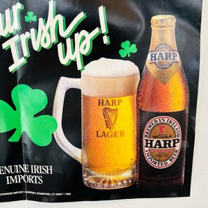 May include: Poster advertising Harp Lager beer, featuring a pint of beer and a bottle. The text reads "Your Irish up!" with shamrock decorations. The poster also states "Genuine Irish Imports."