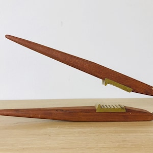 May include: A wooden nutcracker with a brass mechanism. The nutcracker is made of dark wood and has a long, narrow handle.