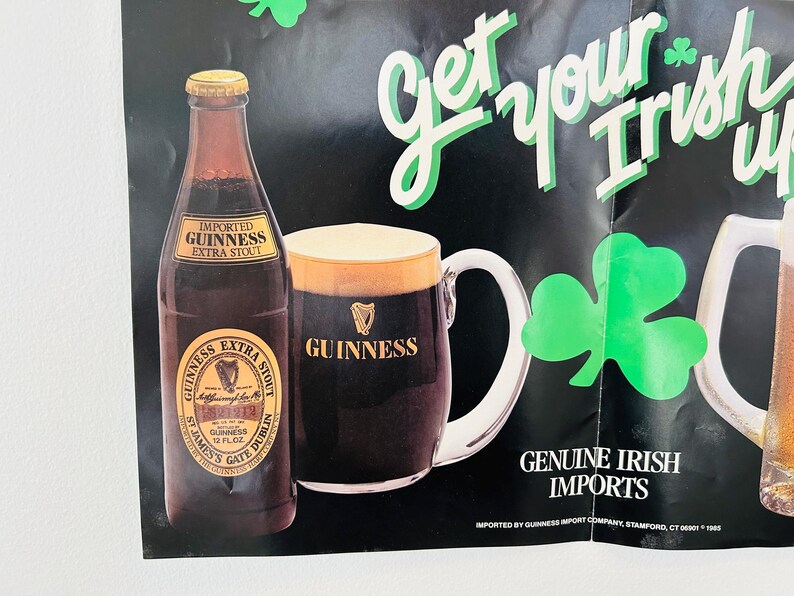 May include: Poster advertising Guinness Extra Stout, featuring a bottle and a pint of the dark stout. The poster includes the text "Get your Irish up" and "Genuine Irish Imports", along with green shamrocks.