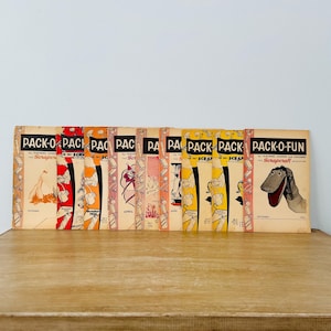 May include: A collection of 12 vintage "Pack-O-Fun" magazines for teachers and children. The magazines feature colorful covers with illustrations of crafts and activities. The text on the covers reads "Pack-O-Fun for Teachers, Parents and Children - Scrapcraft".