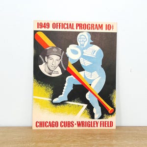 May include: Vintage 1949 Chicago Cubs Wrigley Field official program. The cover features a baseball player in a blue uniform with a red and yellow bat. A portrait of Wayne Waller is in a baseball-shaped frame. Text includes "1949 Official Program 10¢".