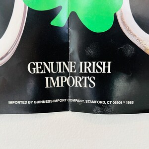 May include: A vintage advertisement featuring the text "GENUINE IRISH IMPORTS" in white on a black backdrop. A green shamrock and a pint of beer are visible. The advertisement is from 1985.