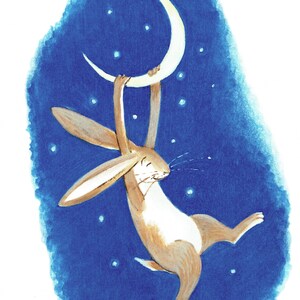 Puede incluir: Un conejo marrón con orejas largas cuelga de una luna creciente contra un cielo nocturno azul con estrellas blancas. El conejo está mirando hacia el lado izquierdo de la imagen y tiene las patas extendidas.