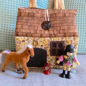 May include: A brown and tan toy house with a stone facade, a small brown horse with a white mane and tail, and a doll wearing a green vest, pink shirt, and black hat.