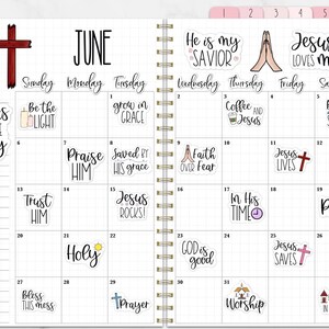 Puede incluir: Un planificador de espiral abierto en junio, con un dise&ntilde;o de cuadr&iacute;cula y pegatinas religiosas. Las pegatinas presentan frases y s&iacute;mbolos como cruces y manos en oraci&oacute;n. El planificador tiene pesta&ntilde;as rosas.