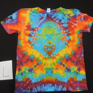 May include: A tie-dye t-shirt with a V-neck and short sleeves. The shirt is a mix of bright colors, including red, orange, yellow, green, blue, and purple. The colors are arranged in a swirling pattern, creating a psychedelic effect. The shirt is size L.