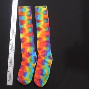 May include: A pair of knee-high socks with a tie-dye pattern in shades of blue, green, yellow, orange, and red.