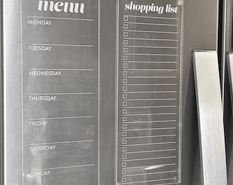 May include: Two clear acrylic magnetic boards with white text. The left board is labeled menu with days of the week from Monday to Sunday. The right board is labeled shopping list with a vertical column of empty checkboxes for itemized entries.