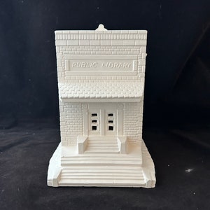 Puede incluir: Modelo de biblioteca pública de cerámica blanca con un letrero que dice "PUBLIC LIBRARY". El edificio tiene una fachada de ladrillo, una escalera y una puerta con ventanas.