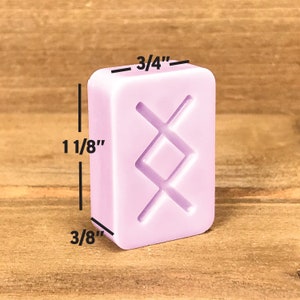 Pode incluir: Um azulejo retangular de cor roxo claro com um desenho geom&eacute;trico branco em relevo. O azulejo mede 3/4 polegadas de largura por 1 1/8 polegadas de altura por 3/8 polegadas de espessura.