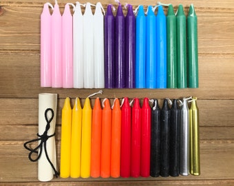 May include: A set of 24 colorful candles, arranged in two rows of 12. The candles are all the same size and shape, and they are arranged in a rainbow pattern. The candles are on a wooden surface.