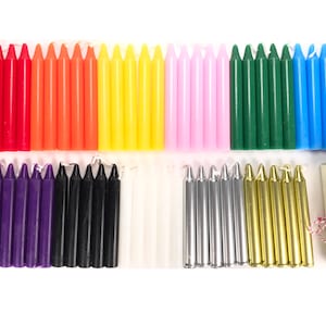 May include: Assortment of colored and metallic taper candles, arranged in rows on a white surface. The candles are approximately 3 inches long and come in a variety of colors, including red, orange, yellow, green, blue, purple, black, white, silver, and gold.