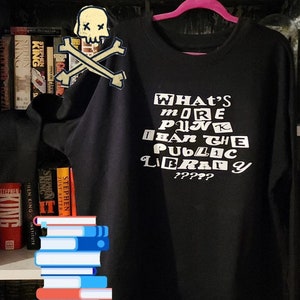 May include: Black long-sleeve shirt with white text that reads "What's more punk than the public library?????"