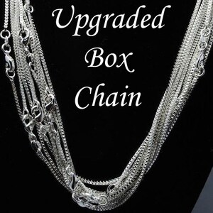Puede incluir: Un collar de cadena de caja de plata. La cadena est&aacute; en capas y tiene un acabado pulido. El texto "Upgraded Box Chain" es visible en la imagen.