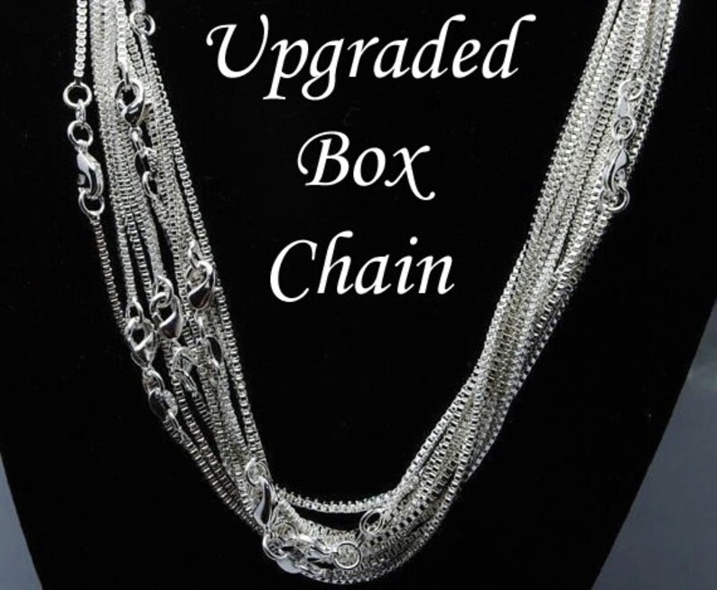 Puede incluir: Un collar de cadena de caja de plata. La cadena est&aacute; en capas y tiene un acabado pulido. El texto "Upgraded Box Chain" es visible en la imagen.