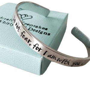May include: A silver metal bracelet with the inscription "Do not fear, for I am with you."