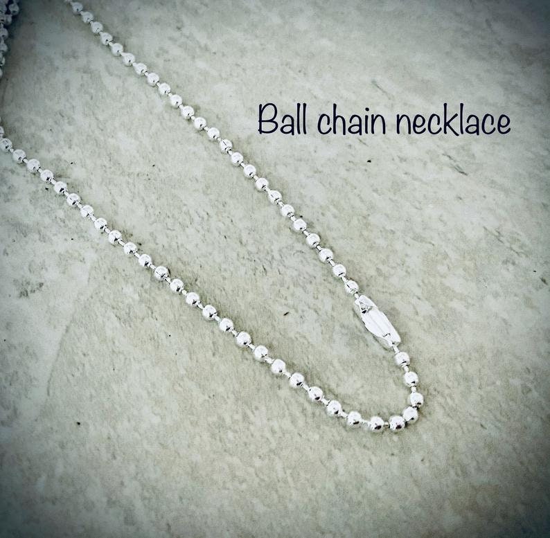 Puede incluir: Un collar de cadena de bolas plateado con cierre de broche. El collar est&aacute; sobre una superficie texturizada gris claro.  "Ball chain necklace" est&aacute; escrito en negro sobre el collar.
