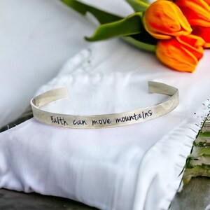 May include: A silver bracelet with the inscription "Faith can move mountains".