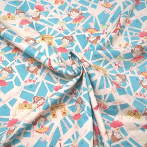 May include: A white fabric with a blue and pink pattern of dancing girls, buildings, and numbers. The fabric is folded in half and the pattern is repeated on both sides.