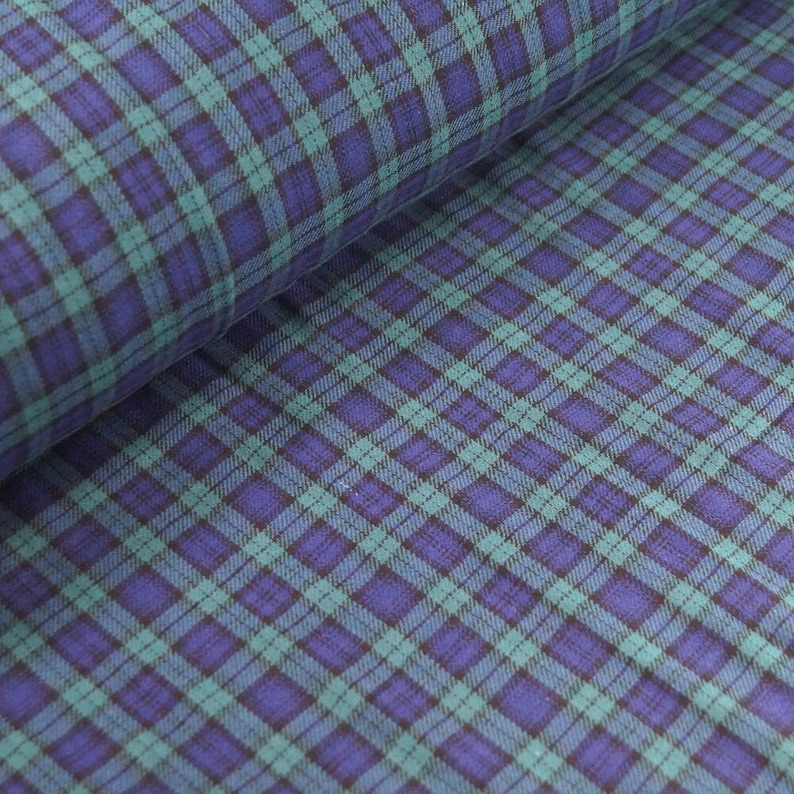 May include: A close-up of a blue and green plaid fabric. The fabric has a soft, textured feel and is perfect for sewing projects.
