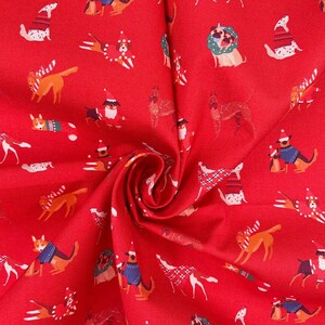 May include: Red fabric with a repeating pattern of dogs wearing Christmas jumpers and hats. The dogs are in various poses and breeds.