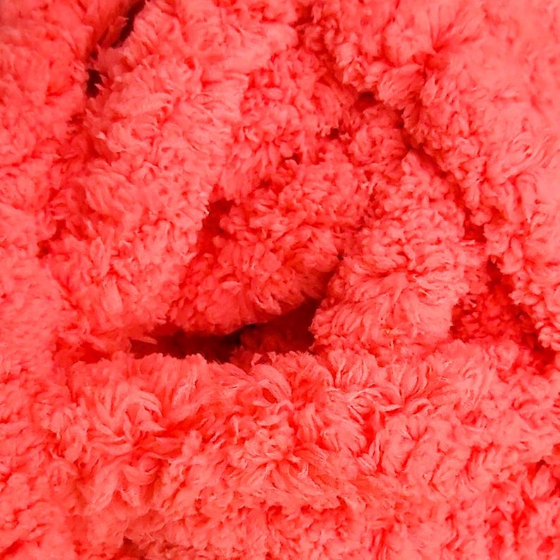 May include: Close-up of a vibrant coral-colored, fluffy textile. The texture appears soft and plush, with a dense, irregular surface. The material is tightly woven, creating a thick, tactile appearance.