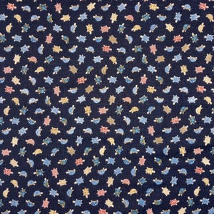 May include: A dark blue fabric with a repeating pattern of small, colourful turtles. The turtles are in various shades of blue, yellow, and pink.