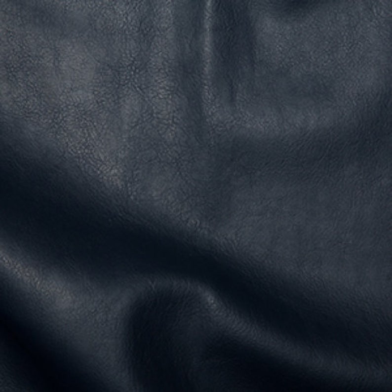 May include: Close-up of a dark blue textured fabric with a wrinkled surface.
