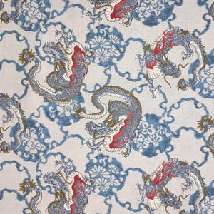 May include: Textile featuring a repeating pattern of dragons in blue, red, and gold on a white backdrop. The dragons are set against a background of blue floral and cloud-like shapes, creating a textured, decorative design.