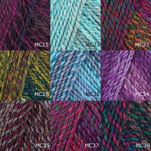Op de afbeelding: Een verzameling van negen garenklossen in verschillende kleuren, waaronder paars, blauw, groen en bruin. Elke klos heeft een uniek kleurpatroon en is gelabeld met een code, zoals "MC15" en "MC27".