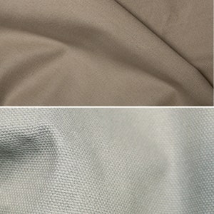 K&ouml;nnte beinhalten: Zwei Stoffmuster, eines in hellbeige und das andere in hellgrau. Beide Muster haben eine gewebte Textur.