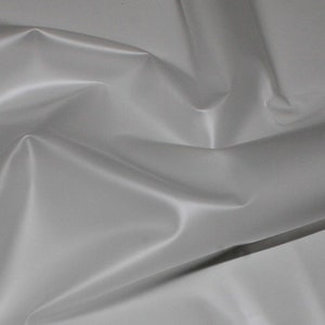 May include: A close-up of a smooth, white fabric with a slight sheen. The fabric is folded and draped, showing its texture and drape.