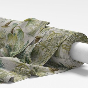 Puede incluir: Un rollo de tela con estampado tropical que presenta hojas de palmera verdes y helechos sobre un fondo beige claro.