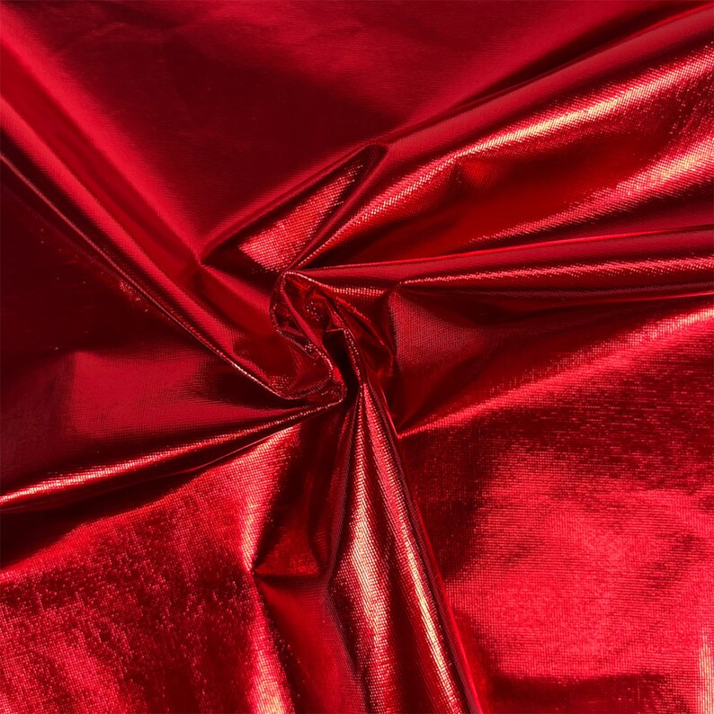 Puede incluir: Primer plano de una tela roja brillante con un acabado met&aacute;lico. La tela est&aacute; doblada y drapeada, mostrando su textura y brillo.