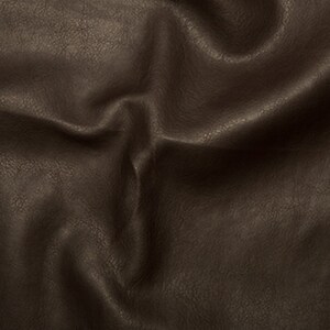 May include: Close-up of a brown faux leather fabric with a textured surface. The fabric is wrinkled and folded, showing the texture and drape of the material.
