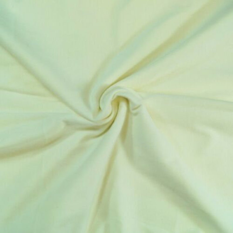 May include: A close-up of a pale yellow fabric, showing the texture and drape of the material.