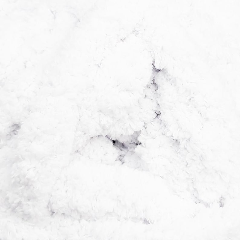 May include: A close-up shot of a white, fluffy, textured surface. The texture appears soft and cloud-like, with subtle variations in tone and depth. The overall impression is one of gentle, light, and airy softness.
