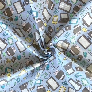 May include: A blue fabric with a repeating pattern of various technology icons, including computers, printers, phones, and music notes. The fabric is folded in the centre, creating a diagonal line.