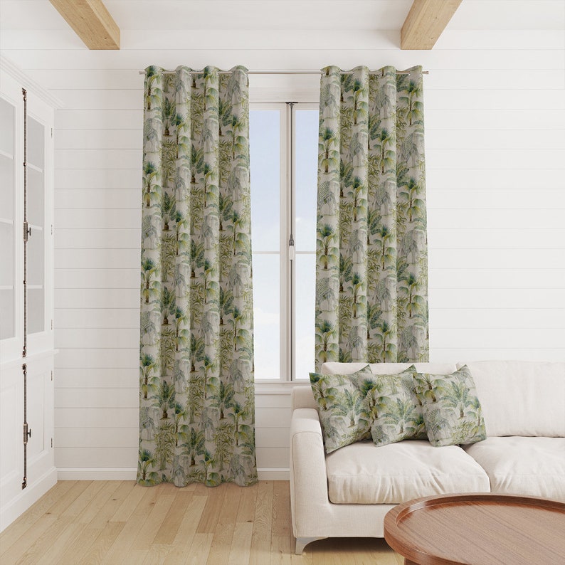 Puede incluir: Una sala de estar con un sof&aacute; blanco y dos cortinas de color verde con estampado de palmeras. Hay tres cojines en el sof&aacute; con el mismo estampado de palmeras que las cortinas.