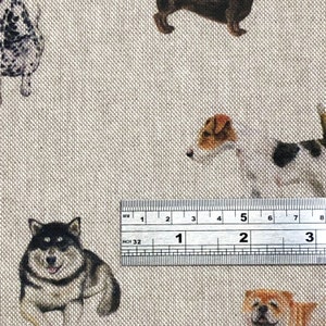 Pode incluir: Um close-up de uma r&eacute;gua medindo 7,6 cm, com um fundo de tecido bege com um padr&atilde;o repetido de v&aacute;rias ra&ccedil;as de c&atilde;es. O tecido apresenta um husky preto e branco, um terrier marrom e branco, um dachshund marrom e um pug marrom e branco.