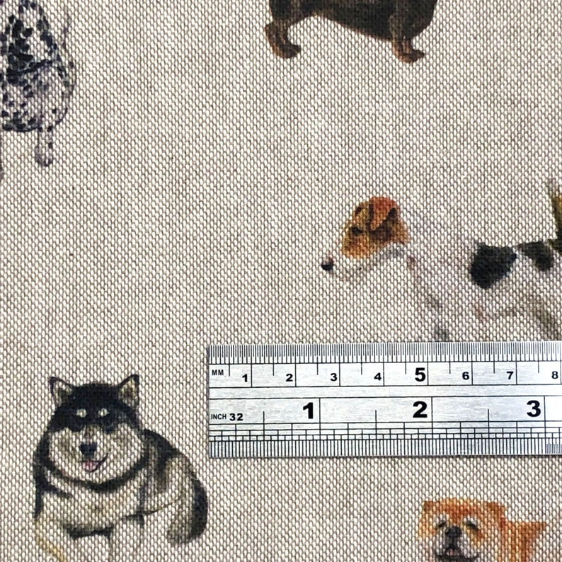 Pode incluir: Um close-up de uma r&eacute;gua medindo 7,6 cm, com um fundo de tecido bege com um padr&atilde;o repetido de v&aacute;rias ra&ccedil;as de c&atilde;es. O tecido apresenta um husky preto e branco, um terrier marrom e branco, um dachshund marrom e um pug marrom e branco.