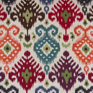 May include: A colourful fabric with a repeating pattern of geometric shapes in shades of orange, red, blue, green, and brown. The fabric has a textured, woven look.