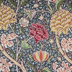 May include: A close-up of a dark blue fabric with a repeating floral pattern. The pattern features red, yellow, and orange flowers with green leaves. The fabric has a textured, woven appearance.